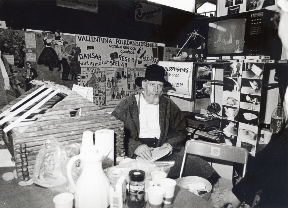 Föreningarna i Vallentuna presenterar sin verksamhet i Vallentuna ishall under mottot Föreningsfestival helgen 19-20 april. Här sitter Alf Olsson i Vallentuna folkdansförenings monter omgiven av skärmutställningar, modell av ett timmerhus och video