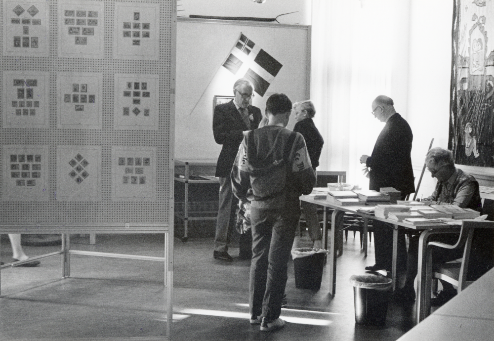 En utställning i Vallentunasalen på Frimärkets dag. Medlemmar i Vallentuna frimärksklubb arrangerar och visar åskådarna. T v står Sven Skoog och stående vid bordet Elis Pettersson