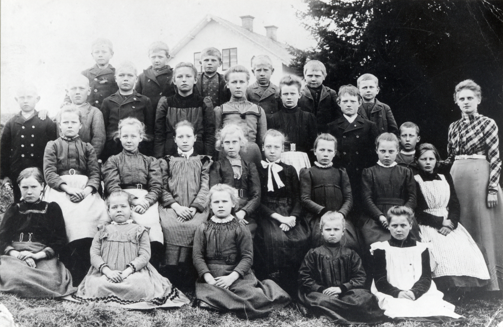 Lärarinnan Julia Jansson-Göransson tillsammans med skolbarnen utanför Berga skola. Övre raden fr v: Bror Ekberg Gullbron, okänd, Elis Karlsson Grana, Henning Stora Mellösa, Aron Gunnar Johansson Andra raden fr v: okänd, Vilhelm Lindö, Emmys bror Tyra Gran Lindö, Edit Johansson Nähle, okänd, Ernst Grönberg Lindö, okänd. Tredje raden fr v: Edla Ekberg Hildur Ekberg Sigrid Linnea Andersson Säby, okänd, Frida Videll okänd, okänd. Fjärde raden fr v: Emmy Elsa Karlsson Grana, Theres Gustafsson Sursta och Eva Åblad