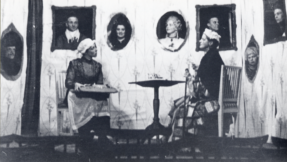 Underhållning vid en fest i Hjälmstaskolans gymnastiksal Föreställningen var Porträtten av A M Lenngren Edit Lindström spelar Hennes nåd, pigan av en småskollärarinna. Porträtten fr v Titus Hahn Rikard Jansson Anna Bergström fröken Tibell (gift Karlsson), ev Holger Hovmark och i vrån Gunnar Lindersson okänd längst t h