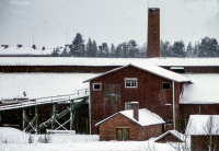 Snötäckta tak på Åby tegelbruk sett från öster. Åby tegelbruk byggdes 1927 av fabrikör C J Gustavsson. Driften lades ner 1968 och bruket brann ner i september 1970. Marken såldes till Riksbyggen.
Bildserie: Vallentuna på 1960-talet.