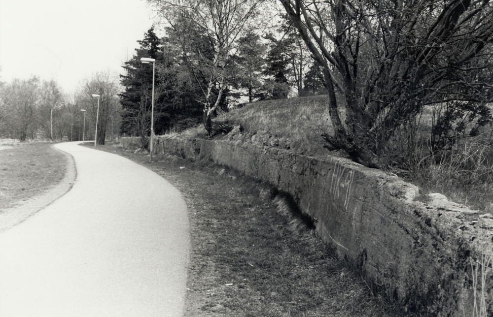 Mur från Vallentuna tegelbruk nedanför Café Bruket  vid gång- och cykelvägen mot  Åby gärde.  Längs muren fanns tidigare ett stickspår som gick från Åby Tegelbruk och förbi Vallentuna tegelbruk ner till Vallentuna järnvägsstation.  Spåret användes för transporter av tegelprodukter till Roslagsbanan