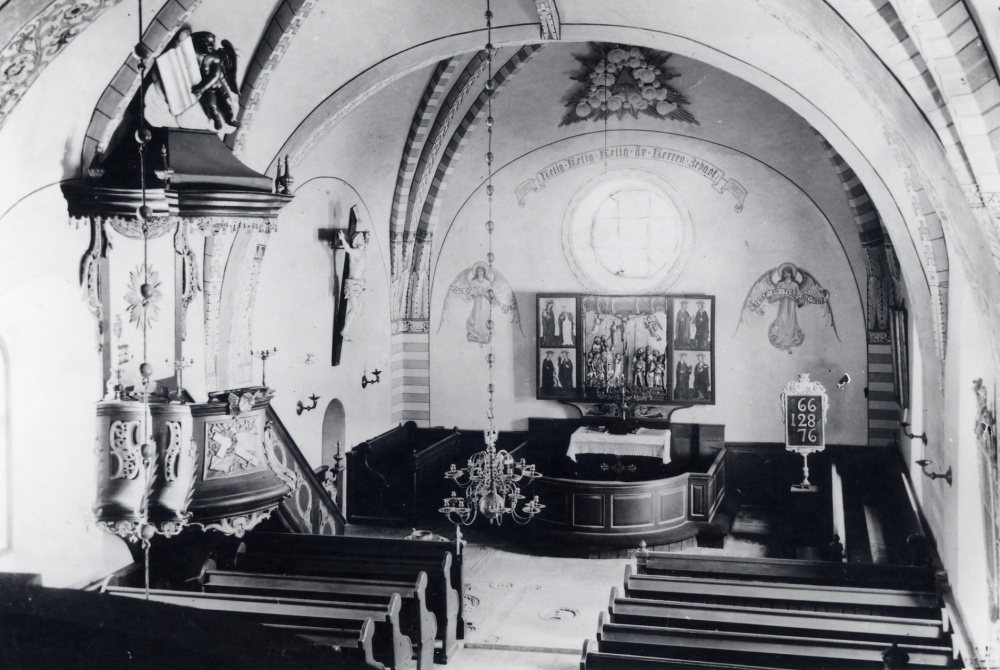 Interiör från Frösunda kyrka 1910. De medeltidsinspirerade väggmålningarna tillkom i samband med en renovering som utfördes 1900. Vid en restaurering, som påbörjades 1952 och var klar pingsten 1953, målades dessa väggmålningarna över helt. Korfönstret och änglarna togs också bort