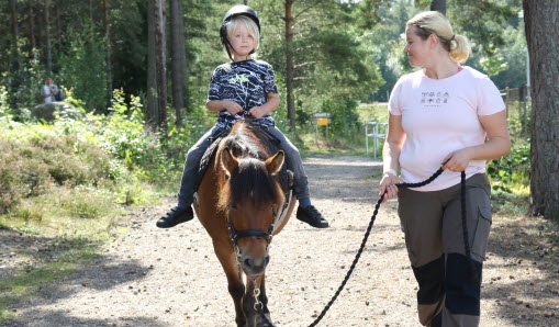 Barn rider på en häst som en ledare leder