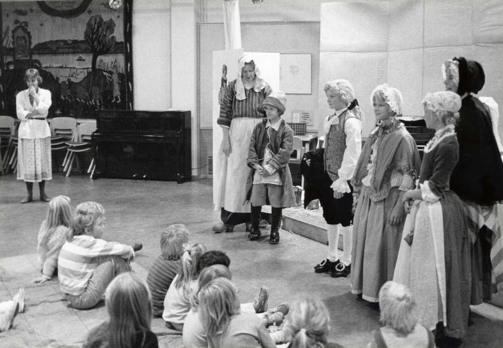 Under tiden 2-31 oktober 1985 pågick i Tärningen utställningar, program, sång, dans, musik och föreläsningar m m under tema På Bellmans tid Arrangörer var föreningar i Vallentuna i samarbete med Kulturnämnden. Idé och utformning: Eva Rahmqvist och Helen Ericsson Här pågår 1700-talet får liv Anne Banér levandegör en målning inför barn och vuxna i Vallentunasalen I programmet ingick projecering av diabilder föreställande en tavla, när sedan draperierna drogs ifrån fanns tavlans personer levande på scenen. Längst t v står Annne Banér. Agerande framför barnen t v Britt Karlsson i svart cape Lena Lundgren