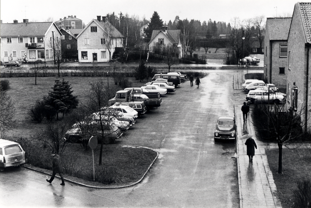 Utsikt från en lägenhet på Skördevägen mot Allévägen. Fr v syns kommunalhusparken och bakom den hus längs Allévägen samt i förgrunden parkeringsplatsen bakom kommunalhuset samt kommunalhusets två gavlar
