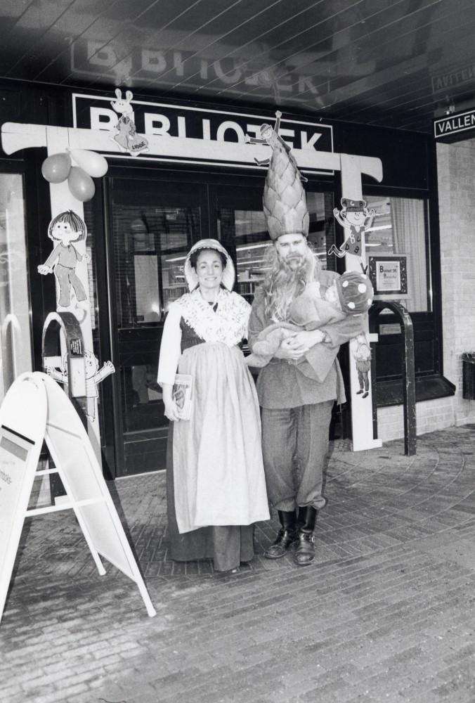 Bokfest 1996 i Vallentuna bibliotek med tema barnkultur.  Vid entrén välkomnar årets presentatörer, Nina Ödlund och Richard Wesemeyer,  klädda som tomtemor och tomtefar från Elsa Beskows  bilderbok Tomtebobarnen