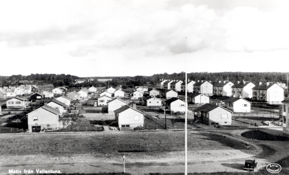 Prästgårdsgärdet i Vallentuna nybebyggt med enfamiljshus.  I bakgrunden skymtar huvudbyggnad, flyglar  och ekonomibyggnader vid Väsby gård.  T h nybyggda flerfamiljshus med bostadsrätter längs Allévägen