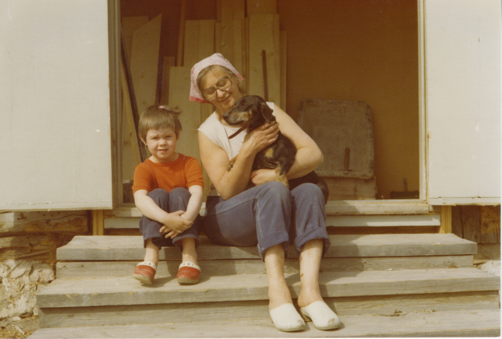 På trappen sitter Ingrid Jacobsson och flickan Anna-Karin Uddén ca 4 år. Ingrid har en tax i knäet. Troligtvis är det trappen till klockstapeln vid Vada kyrka.