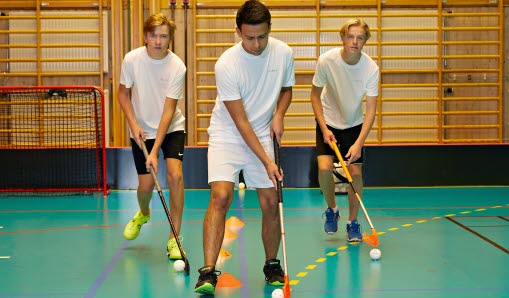 Tre pojkar som spelar innebandy