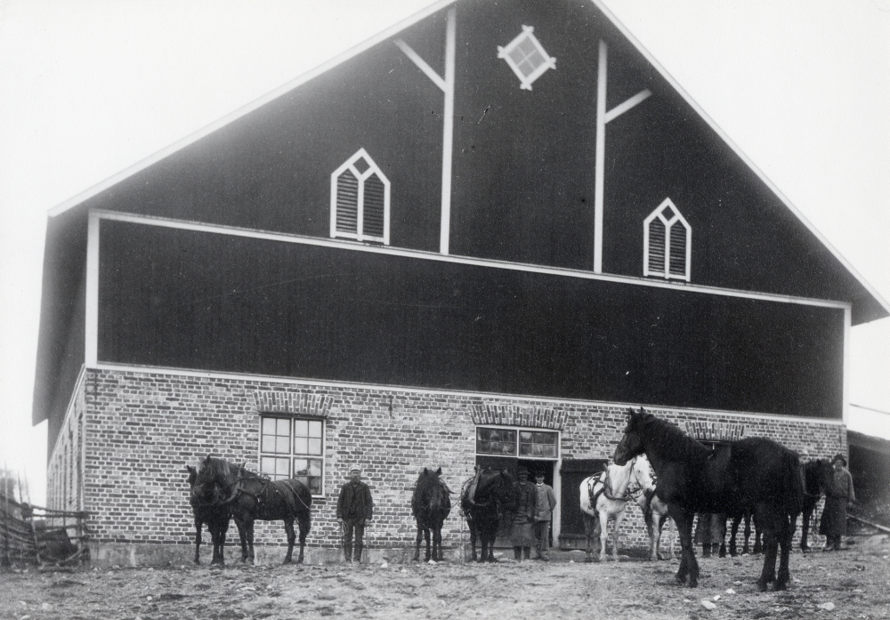 Ladugården på Backa gård i Kårsta.  Ladugården byggdes 1900. I dörren står gårdens ägare Sven Lindgren och bredvid honom Karlsson i Smedtorp.  T v står Lundkvist.  Framför ladugården står gårdens hästar. 1915 flyttade familjen Lindgren till Erna gård.  Sonen Erik Lindgren köpte tillbaka Backa gård på hösten 1943 och flyttade in på nytt 1944