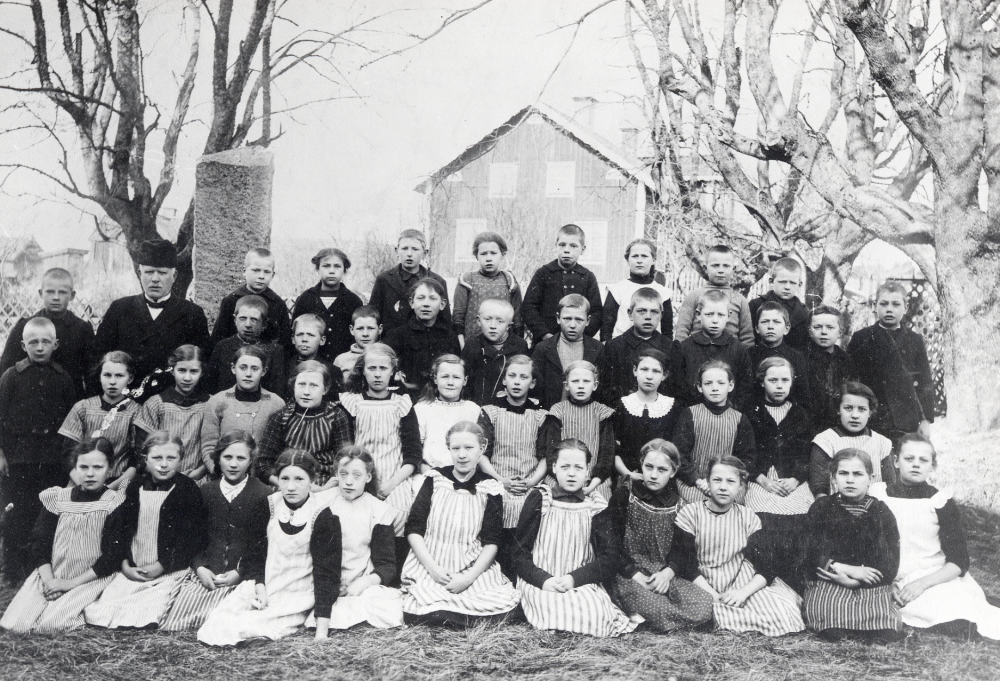 Läraren Fritiof Sundell tillsammans med skolbarnen utanför Kårska kyrkskola. Bakre raden fr v Henning Lundin, läraren Fritiof Sundell, okänd, okänd, August Berglund, Karin Jansson, okänd, Rut Gustavsson, Gösta Sundberg och Gösta Lindkvist. Rad 2 fr v okänd, Sven Jansson, Georg Andersson, Erik Sundkvist, Nisse Sundkvist, Valter Bergman, Klas Bergman, Nils Karlsson, okänd, Bror Eklöv, John Törnkvist, Edvin Johansson. Rad 3 fr v Gertrud Lundberg, Svea Lundberg, Lilly Kraft, Eva Johansson, Märta Sundberg, Elsa Gustavsson, Lilly Andersson, Sigrid Lundberg, Elvan Sundkvist, Ester ?, Thyra Andersson och Ingrid ?. Rad 4 fr v Gärda Lundgren, Gärda Karlsson, Greta Raab, Thyra Viman, Rut Jansson, Elsa Gustavsson, Linnea Jansson, Gundborg Ländin, Elsa Eriksson, Helga Eriksson och Anna Lönn