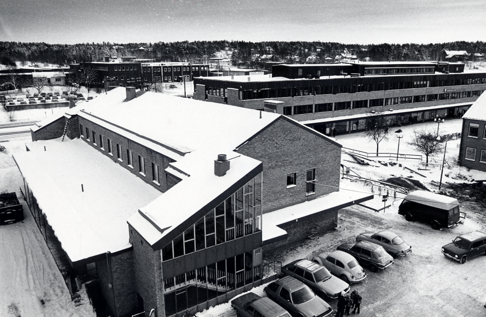 Utsikt  över  Tuna torg  från det hus som fick heta  Tärningen  I förgrunden  Konsumhuset  med parkerade bilar väster om huset samt  Tunahuset  I bakgrunden t v  Tellus Maskin  Längst t h skymtar en gavel på  kommunalhuset