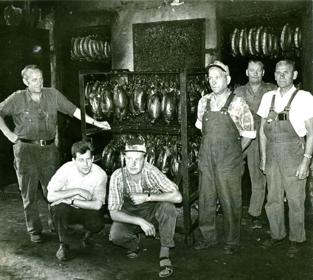 Rökeriet låg på Bällstalundsvägen.  Rökerimästare Skyllberg står längst till höger i bilden. Eventuellt sitter en annan medlem av släkten Skyllberg på huk i randig skjorta.