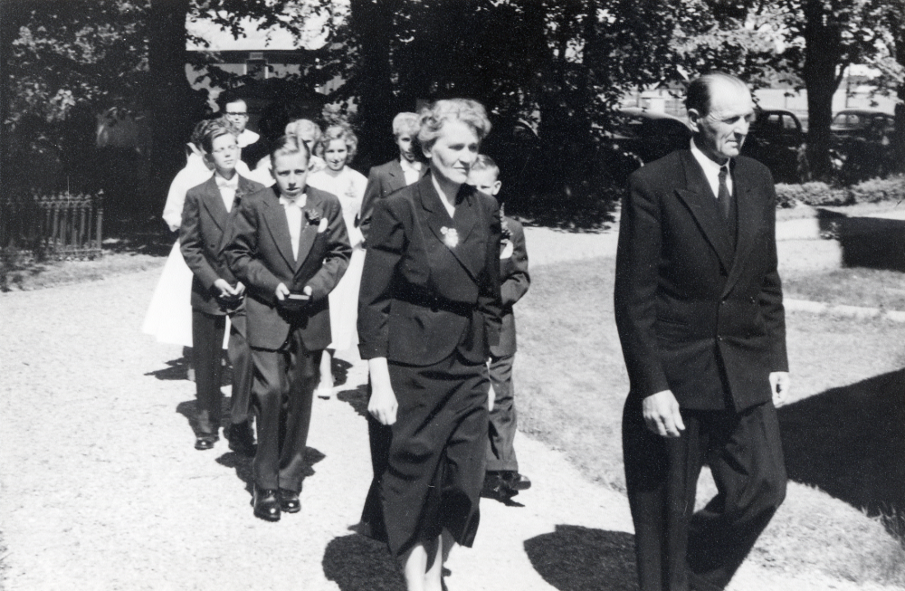 Konfirmation i Frösunda kyrka.  I täten före konfirmanderna går de två kyrkvärdarna Signe Andersson och Fritz Andersson. I första raden fr v Tore Eriksson och Bo Eriksson, rad 2 Nils Johansson och Arne Jansson, flickan mellan pojkarna är Lilian Österberg. Längst bak kyrkoherde Gösta Dahlsten, övriga ansikten skymda