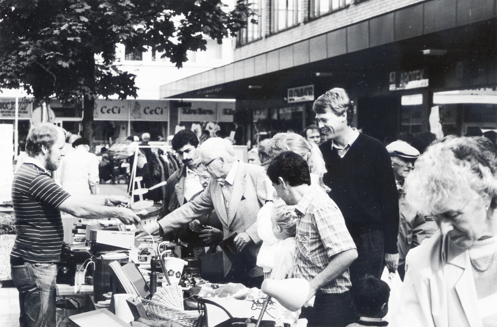 Vallentuna marknad på Tuna torg den andra lördagen i september, arrangerad av Vallentuna hembygdsförening. Här är ett stånd med loppmarknad. T h syns Tunahuset och t v Torghuset