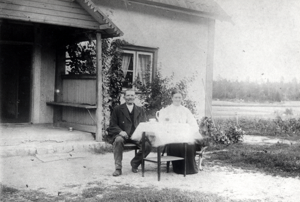 Edla Gustavsson och maken Gustav Gustavsson sitter vid kaffebordet utanför Björkby gård