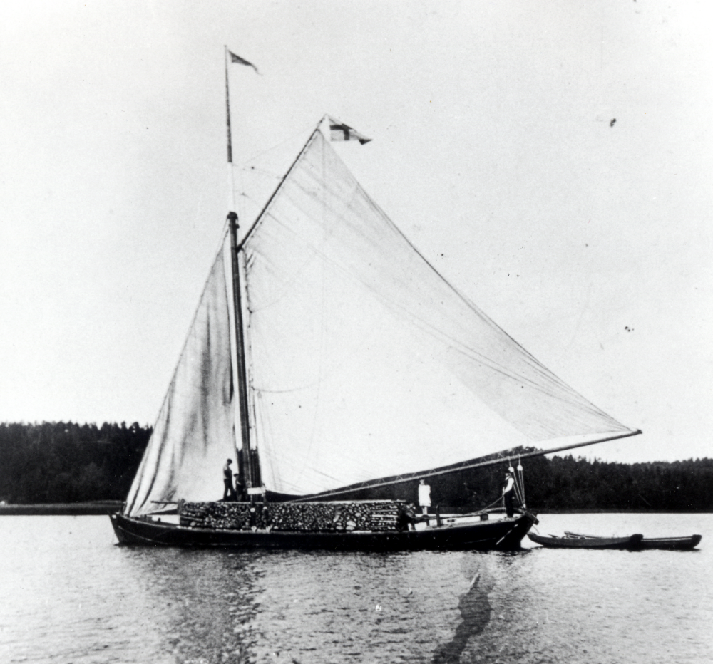 Roslagsskutan Alcea lastad med ved på Garnsviken. 

På originalkortets baksida har någon av syskonen Söderberg i Klockarborg antecknat: "Det här kortet blev motiv till Österåkers vapen"