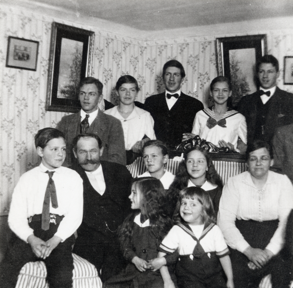 Emanuel och Elin Johansson tillsammans med tio av sina barn.  I äktenskapet föddes 16 barn, 13 nådde vuxen ålder.  I bakre raden fr v Fredrik, Helga, Helge, Svea och Gösta.  I soffan sitter fr v Seth, fadern Emanuel, Alice, Signe,  modern Elin samt framför flickorna Margit och yngste sonen Karl-Erik.  Barnen Karin, Sven och Bengt saknas. Alla barnen antog senare släktnamnet Helgöstam