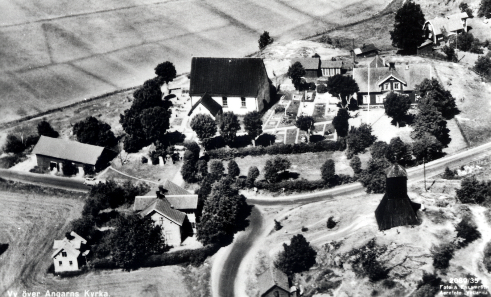 Flygfoto över Angarns kyrkby.  I förgrunden t v Karlborgs handelsbod.  Det  stora huset t h om kyrkan är Angarns kyrkskola