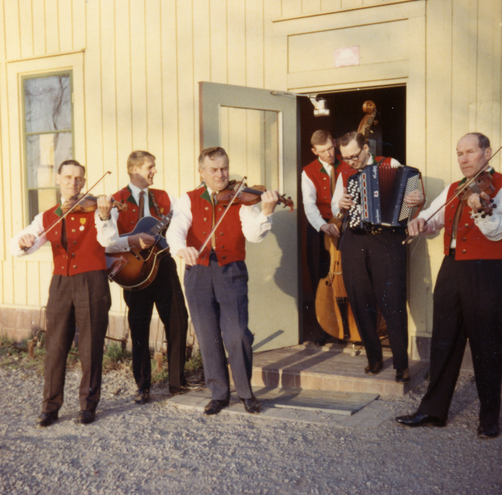 Orkesta spelmanslag, fr v Enar Lundqvist, Lennart Jansson, Åke Mattsson, okänd, Forsberg och Sven Wahlström. Spelmännen står i dörröppningen på baksidan av Lindholmens järnvägsstation