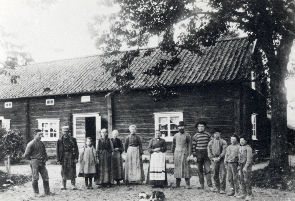 Arrendatorsbostaden vid Frösunda prästgård. Prästgården och den östra flygel revs 1917. Mannen i mitten med mörkt skägg är arrendatorn M W Mattsson och kvinnan i ljust förkläde är hans hustru