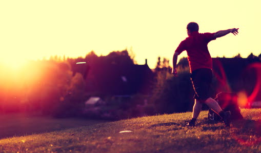 En man som kastar frisbee i solnedgången