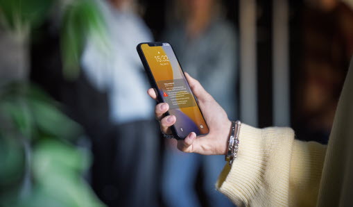 Hand som håller en mobiltelefon med ett larm på skärmen