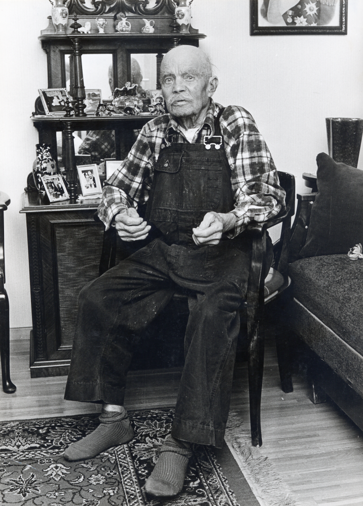 Carl Johan Pettersson "Brännarpelle"  i sin bostad Norrgården 30.  Han var i många år brännare vid  Åby tegelbruk  och kommunal- och facklig förtroendeman. Född 23 september 1877 var han Vallentunas äldste invånare när kortet togs.  Han var erbjuden att flytta till Väsbygården, men ville bo kvar i sin lägenhet där han dog 1975.  Hans hustru  Anna Pettersson  född 1882, dog i januari 1974.

2022-01-17 Uppgifter från Kyrkoarkiven: Paret hade döttrarna Svea född 1904, Linnéa 1908 och Ingrid 1910.
2021-07-08 Uppgifter från svenskagravar.se: Pettersson, Karl Johan levde 1877-09-23 till 1975-06-19. Gravsatt: 1975-06-28 Vallentuna kyrkogård. Pettersson, Anna Maria levde 1882-12-15 till 1974-01-27. Gravsatt: 1974-02-09 Vallentuna kyrkogård