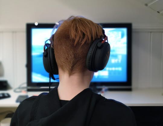Pojke med hörlurar som sitter framför en dator