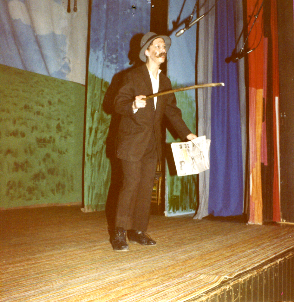 Össebyamatörernas revy "På vårkanten" 1982. På scenen står Inger Uddén som Otto Grepe som förmedlar förnumstiga och vassa kommentarer om politiken som det stått om i tidningarna. Lokal: Karbyskolans gymnastiksal.