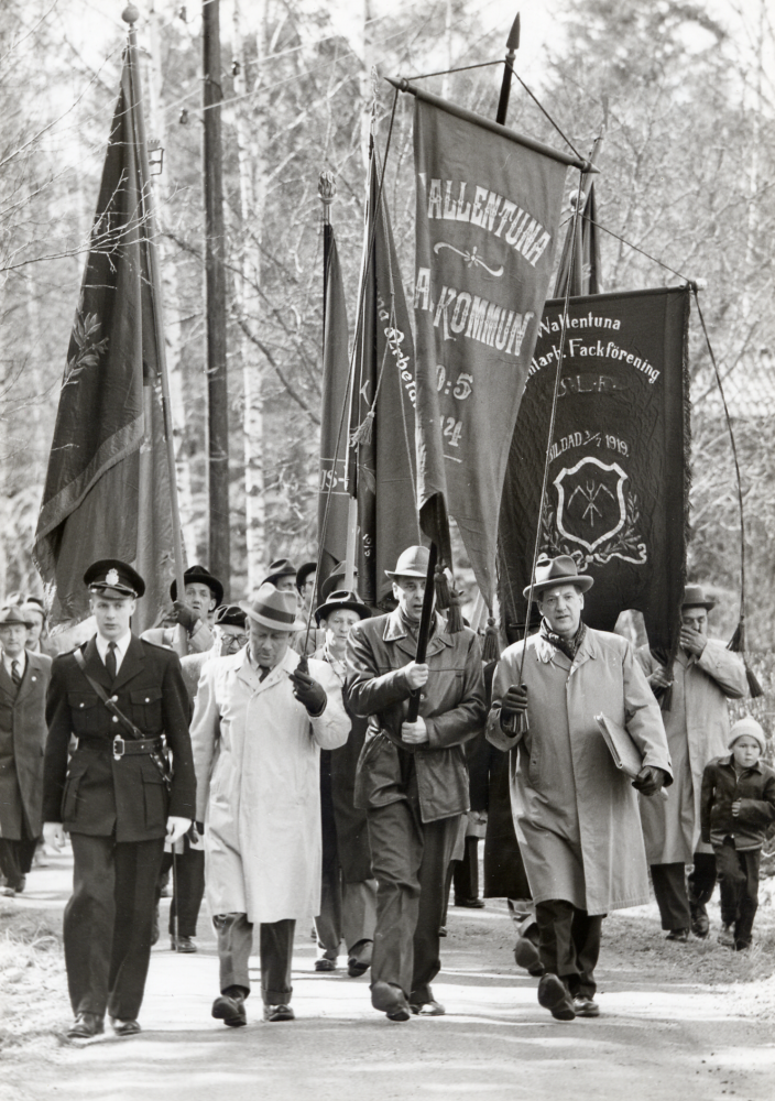 Första maj-demonstration  i Vallentuna, 40 år efter en första demonstrationen som ägde rum 1917. I täten på tåget går  Elof Österberg ,  Åke Ekström  som bär fanan och talaren  Edvin Thun     Ur Josef Andersson,Vallentuna socialdemokratiska arbetakommun 1914-1964