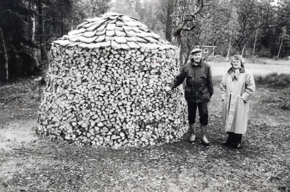 Malte Brunnberg och Kajsa Sandqvist bredvid den runda vedtraven vid Björkhaga, Lingsberg i Vallentuna