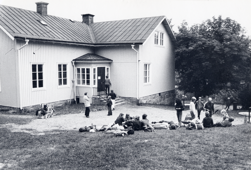 I  Össeby-Garns kyrkskola  finns  Vallentuna lägerskola  i bottenvåningen. Hit åker Vallentunas barn i årskurs 5 för i två dagar leva lägerliv och göra utflykter. Här har klass 6  från  Karlbergsskolan  samlats för avfärd efter avslutat läger. I vit jacka läraren  Agneta Norrlinder  och uppför trappan går lägerskolans föreståndare  Bosse Gårdstad