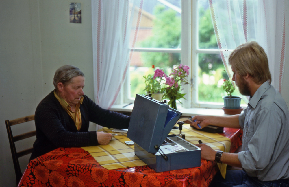 En arbetsdag med lantbrevbärare Mikael Mattsson. Lantbrevbäring i Skesta;  John Andersson (förmodligen jordbrukare) sitter i sitt kök tillsammans med lantbrevbärare Mikael Mattsson i Skesta. Hans son Arne tog över gården och är åkare.