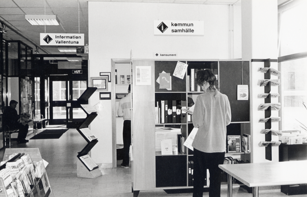 Information Vallentuna i bibliotekets foajé.  Med ryggen mot kameran står Lisa Rune.  I  konsumenthörnan skymtar Åke Holmberg