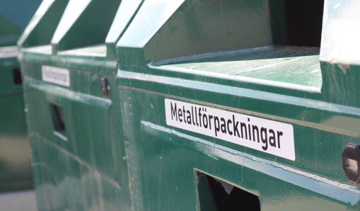 Närbild på gröna containrar på återvinningsstation