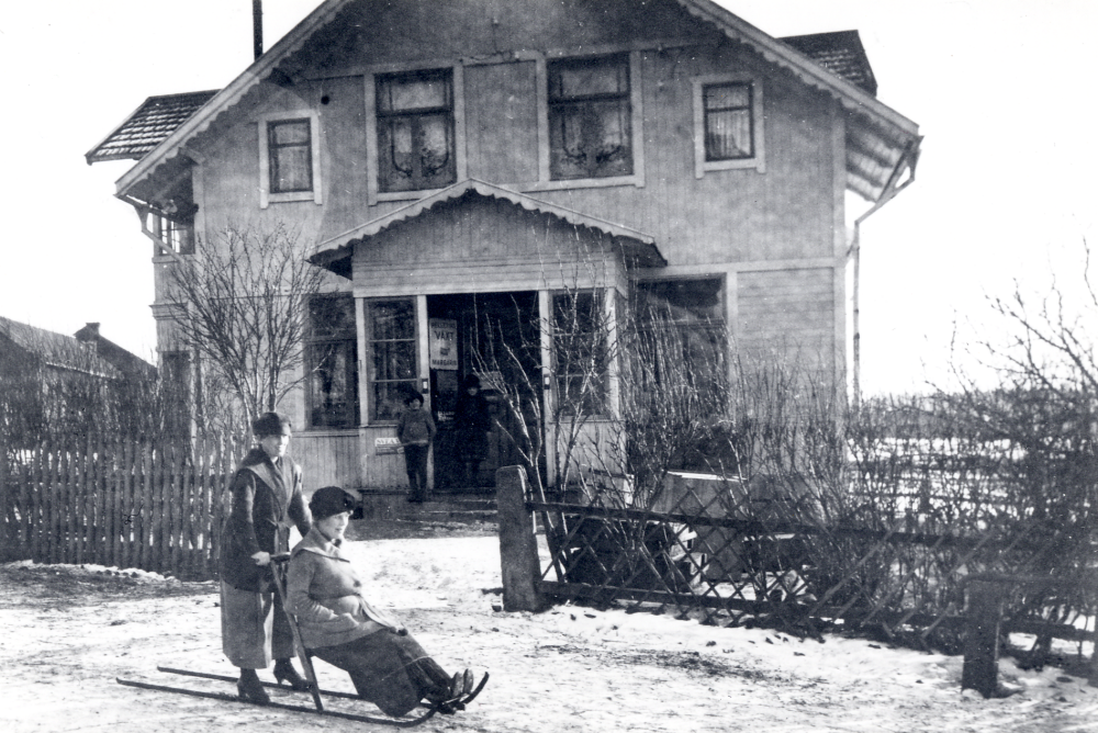 Karlborgs handelsbod  öppnades 1901 och hade byggts av  Carl August Lundin.  Affären låg mittemot Angarns kyrka. 1912 dog C A Lundin, hans hustru  Nanna Lundin  drev affärsrörelsen ensam fram till 1916, då hon hyrde ut butiken. Från 1918 arrenderade  Edvard Johansson  och hans hustru  Signe Johansson  affären. Edvard dog 1938, men Signe fortsatte ensam till 1948.  Folke Renegård  tog då över driften. Butiken blev moderniserad 1950. Siste affärsmannen blev  Rune Westberg  som övertog affären 1954. 1956 köpte han hela fastigheten. Affären var i drift fram till 31 januari 1969. På bilden står  Edla Jansson  på en  spark  och ger dottern Signe Johansson skjuts.  Se: Lanthandlare i vallentunasocknarna vid Roslagsbanan.