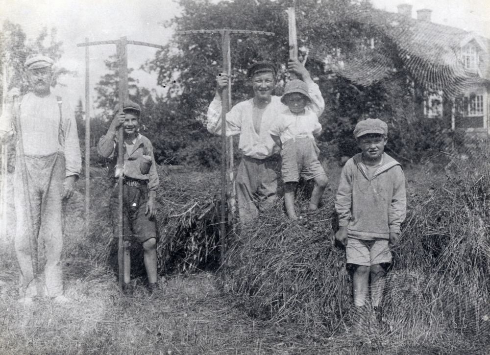 Verner Hedlund, mjölnare vid Granby kvarn i Orkesta, slår hö tillsammans med sina söner.  Fr v står Verner (1887-1954), Martin (1913-1993), David (1910-1952), Holger (1921-1997) och Robert (1918-1993).  Huset i bakgrunden t h är lärarbostaden.  Gösta Andrén var lärare i Orkesta