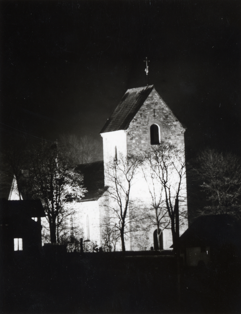 Vallentuna kyrka i strålkastarsken sedd från väster mot tornet