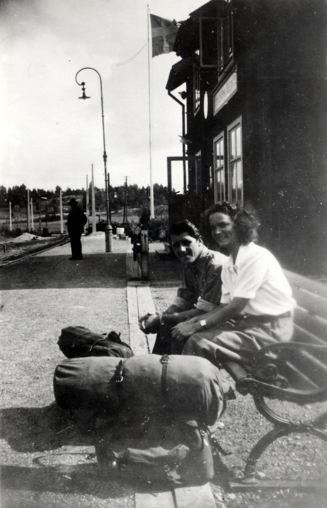Ingegerd och Åke Ahlgren sitter på en soffa utanför Ekskogens stationshus på väg att resa på semester.
Ingegerd och Åke Ahlgrens bad stinsen Aldor Andersson ta denna bild med deras kamera före avfärden från Ekskogen