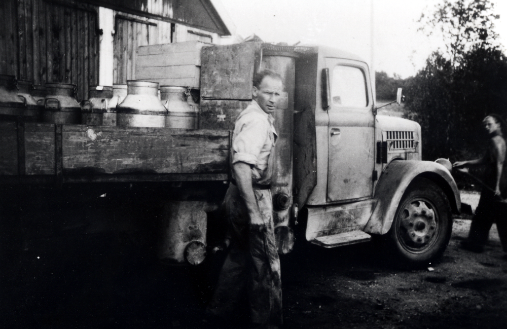 Alstermarks åkeri.  Nils t v och Rune Alstermark vid Lovisedal i Vada.  På lastbilens flak står en mängd 50 liters mjölkflaskor. Bakom förarhytten syns gengasaggregatet