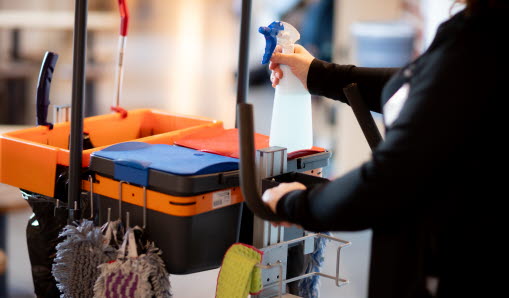 Medarbetare håller i städvagnens handtag