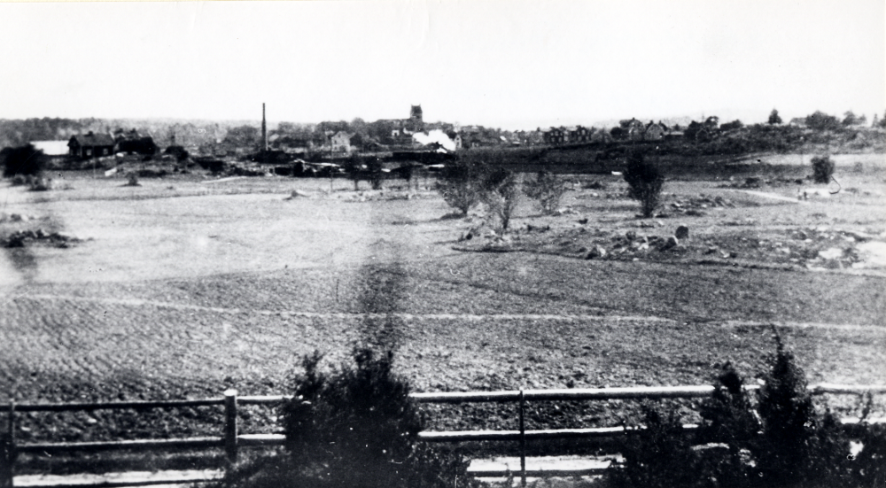 Utsikt från Ormsta gård mot Vallentuna kyrka och stationssamhället. T h Rickebyhöjd, Vallentuna kyrka i mitten och vit rök från ett ånglok på Roslagsbanan. Den höga skorstenen tillhör ett av tegelbruken