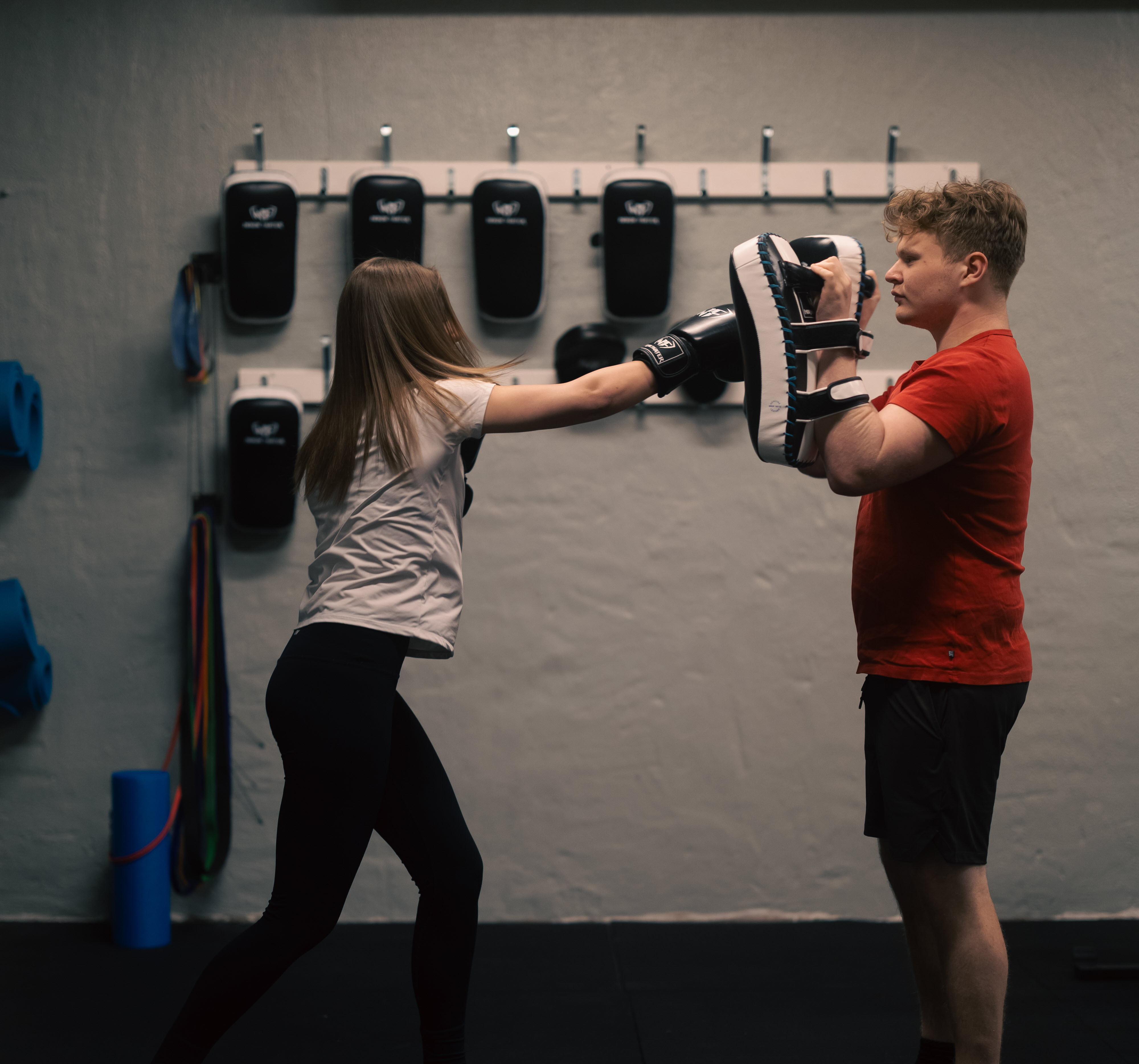 En elev med boxhandskar slår på mittsar som den andra eleven håller upp.