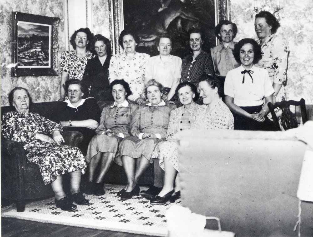 Lottorna träffas i Greta Andreassons bostad ovanpå affären vid Björkebo, Lindholmsvägen i Ormsta.  Stående bakom soffan fr v Greta Andreason, Märta Uhrenius, Elin Lindblad, Gurli Hofgren, Ester Nyberg, Karin Gustafsson och Ester Engström.  Sittande i soffan fr v Jenny Ståhl, Lilian Ekström, Margareta Andersson, Greta Franzén, Alma Sandin och Tora Lundquist.  På armstödet sitter Ingrid Enström