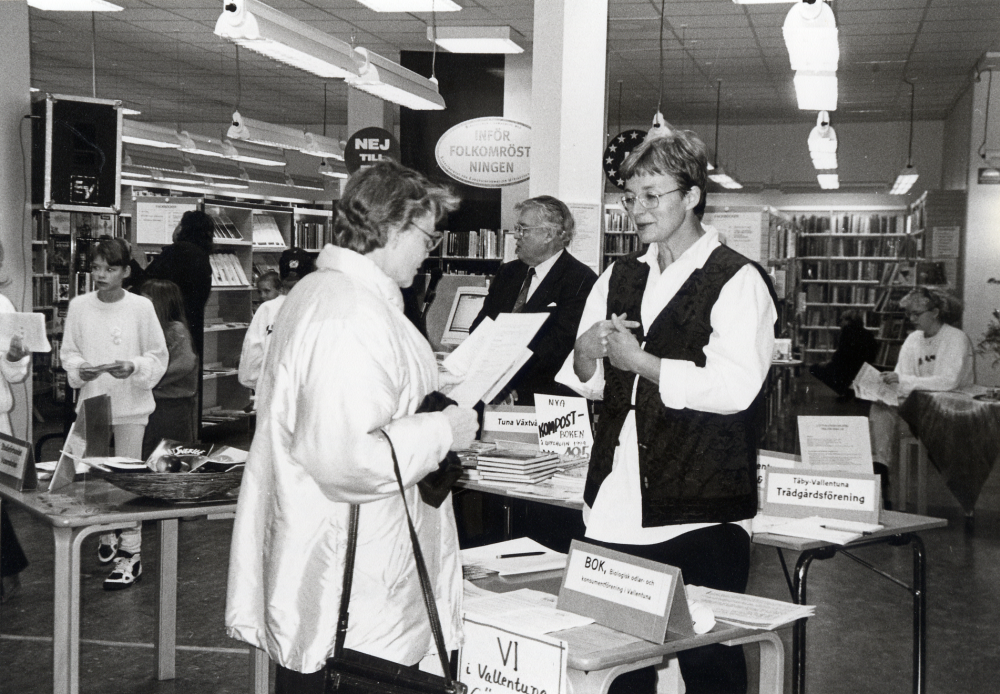 Bokfest  1994 med tema Från Rio till Vallentuna – startskott för Agenda 21-arbetet i Vallentuna kommun.  Föreningar i Vallentuna presenterar en miljövänlig verksamhet.  I förgrunden samtalar Charly Hulthén från BOK i Vallentuna (Biologisk odlar-  och konsumentförening) med Ulla Öhman