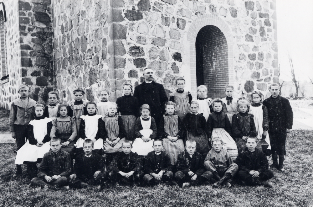 Skolfotografi  utanför  Vallentuna kyrka  Läraren  Per Ferdinand Torell  tillsammans med barnen. I övre raden nr 3 från höger står  Anna Johansson  från  Oppgården