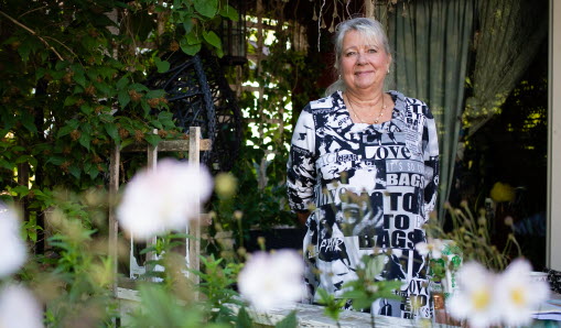 Anette står på sin altan, i förgrunden syns vita blommor