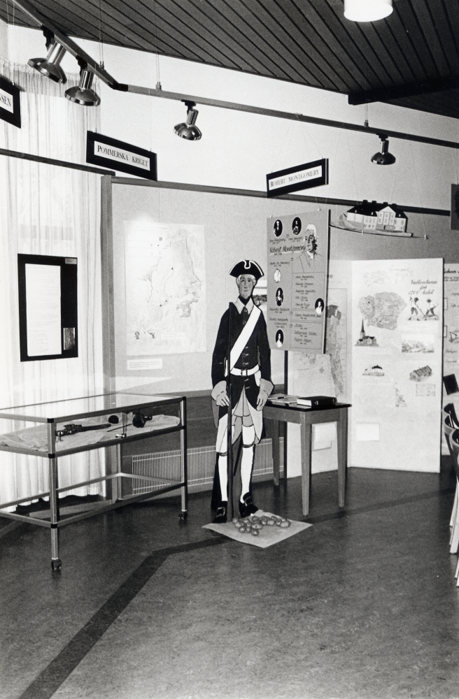 Eva Rahmqvist och Iréne Gustafson från kulturförvaltningen har under historieåret 1993 tillsammans med hembygdsföreningarna i Vallentuna producerat utställningen 1700-tal i Vallentuna.  Här sitter står en soldat från Pommerska kriget vid en monter med bl a vapen utlånade från Husby gårdsmuseum.  Framför soldaten ligger potatis